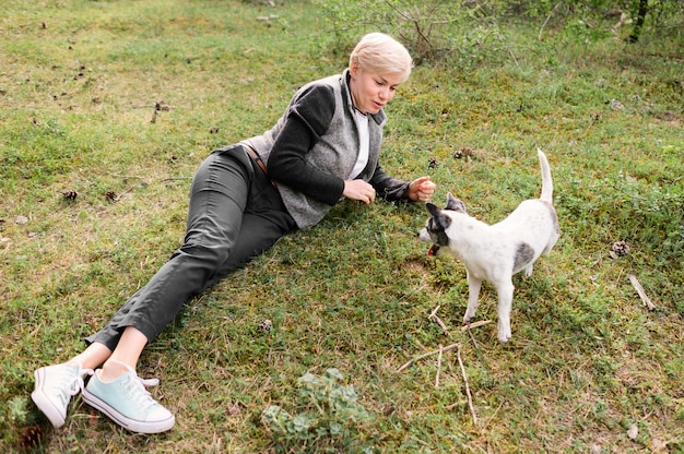 Free photo young woman playing with her dog outdoors