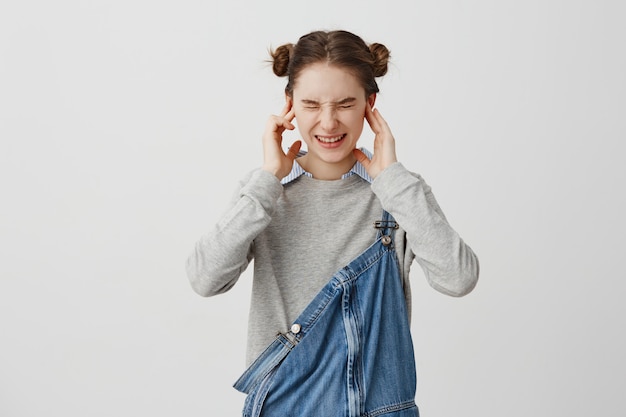 Free Photo young woman plugging ears with fingers and screwing up her eyes in displeasure. brunette female 20s covering ears not listening ignoring conversation.