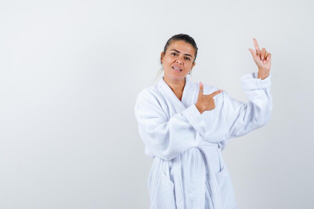 Young woman pointing aside in bathrobe and looking happy