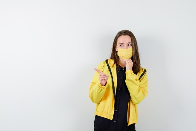 Young woman pointing left with index finger