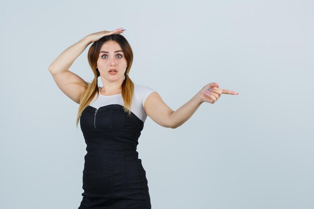 Young woman pointing right with index finger