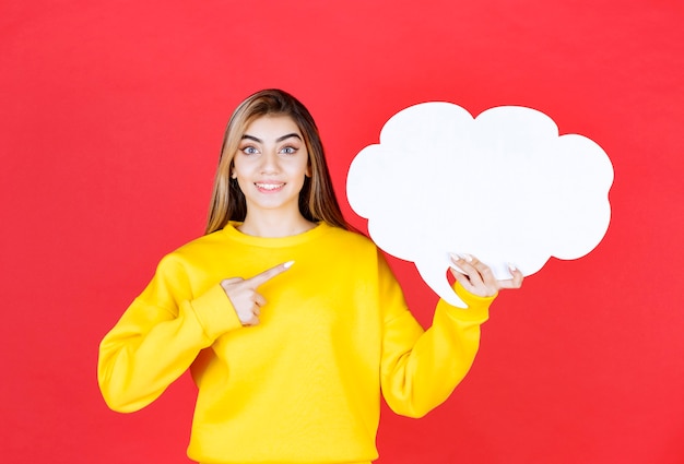 Young woman pointing at a speech bubble on red