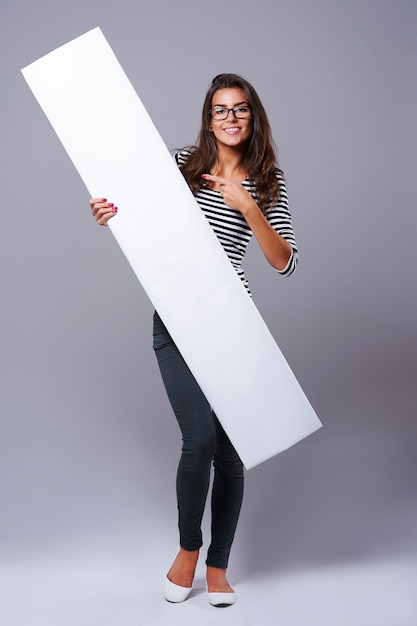 Free Photo young woman pointing on white billboard