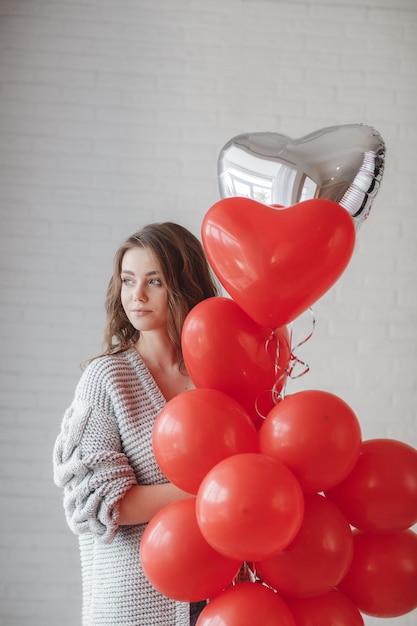 Free photo young woman portrait with red ballons indoor