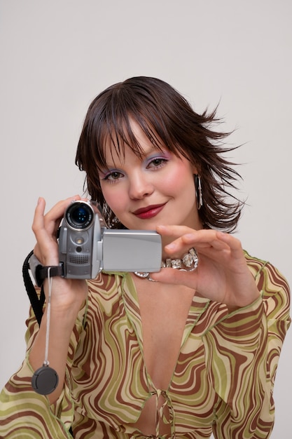 Free photo young woman posing in 2000's fashion style and holding camera