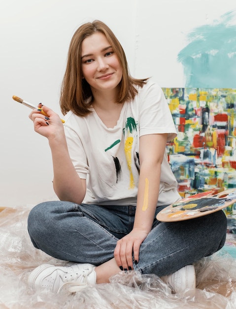 Free photo young woman posing next to her colorful painting