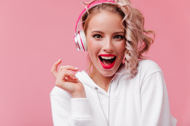 Free Photo young woman posing and listening to music through her pink headphones