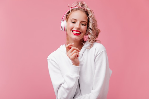 Free Photo young woman posing and listening to music through her pink headphones