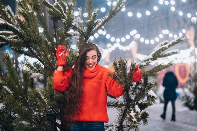 Young woman posing near the Christmas tree on the street