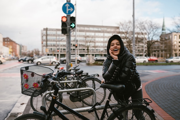 Free Photo young woman posing in a parking lot with bicycles