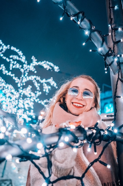 Free photo young woman posing at the street with illuminated trees