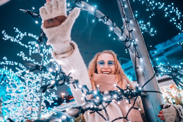 Free photo young woman posing at the street with illuminated trees