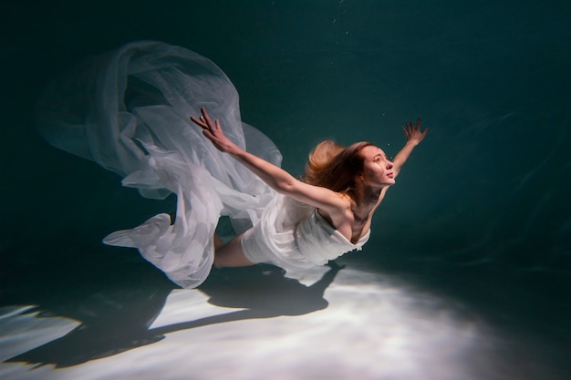 Free photo young woman posing submerged underwater in a flowy dress