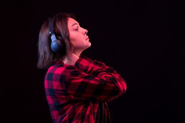 Young woman posing wiht checkered red and black shirt using headphones