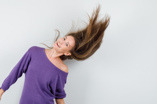 Free photo young woman posing with blowing hair in violet shirt and looking charming , front view.