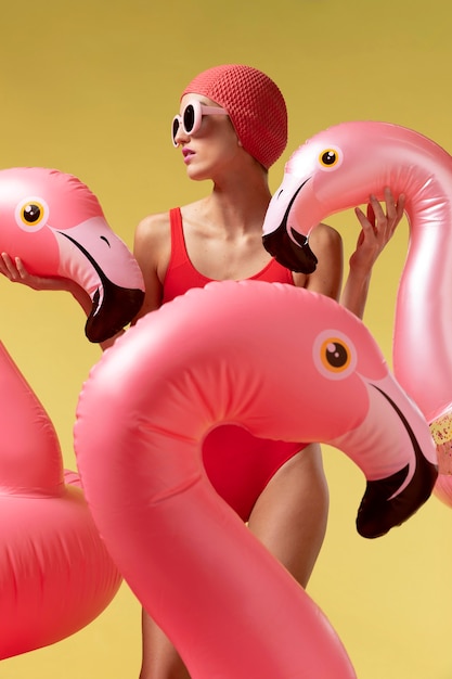 Free photo young woman posing with flamingo swimming ring