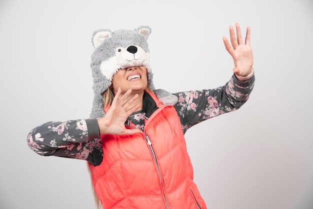 Free photo young woman posing with funny hat on a white wall.