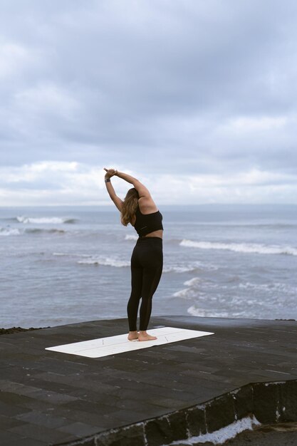 Young woman practice yoga on a beautiful beach at sunrise. Blue sky, ocean, waves, proximity to nature, unity with nature.