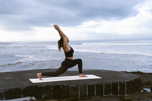 Young woman practice yoga on a beautiful beach at sunrise. Blue sky, ocean, waves, proximity to nature, unity with nature.