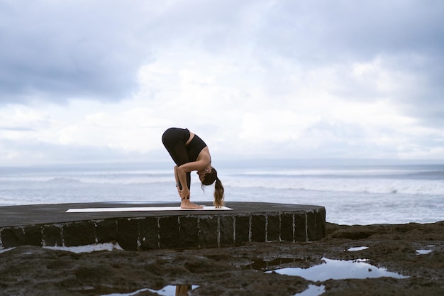 Young woman practice yoga on a beautiful beach at sunrise. Blue sky, ocean, waves, proximity to nature, unity with nature.