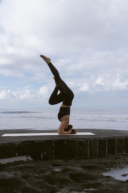 Young woman practice yoga on a beautiful beach at sunrise. Blue sky, ocean, waves, proximity to nature, unity with nature.