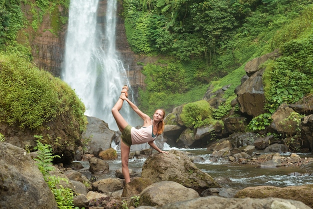 Free Photo young woman practicing yoga by the waterfall