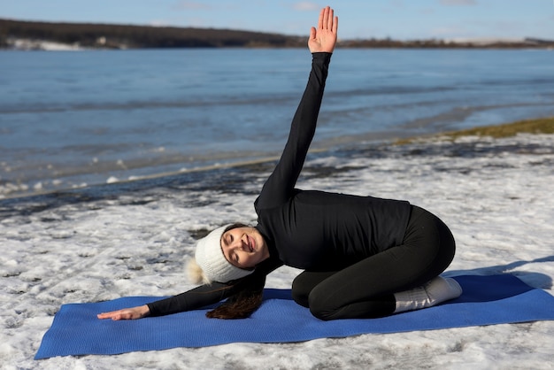 Young woman practicing yoga outdoors during winter on the beach