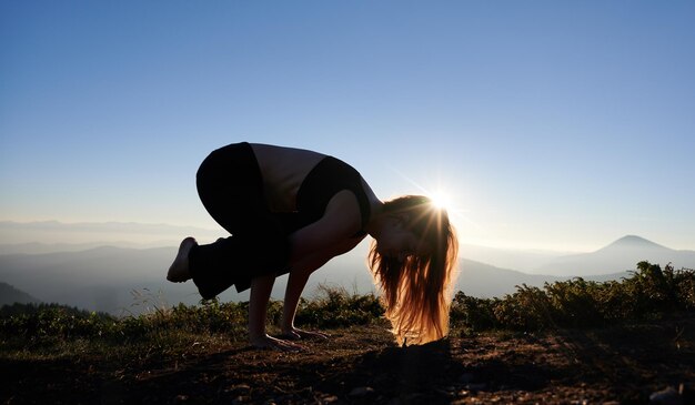 Young woman practicing yoga during sunset in mountains