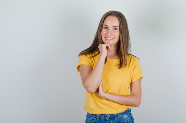 Young woman propping chin on fist in t-shirt, shorts and looking focused