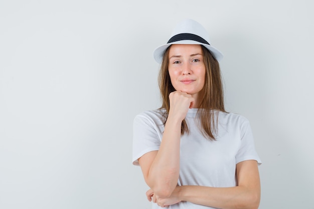 Free Photo young woman propping chin on hand in white t-shirt, hat and looking confident.