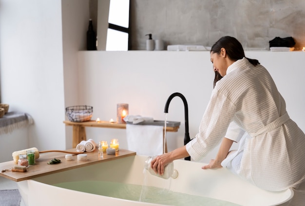 Free photo young woman putting bath salt in the water before taking a bath