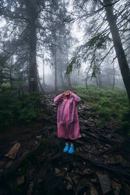 Free Photo young woman in a raincoat walks through the forest in the rain