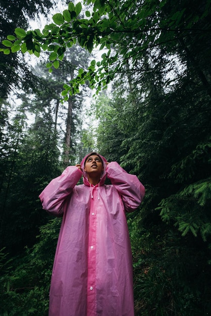 Free Photo young woman in a raincoat walks through the forest in the rain