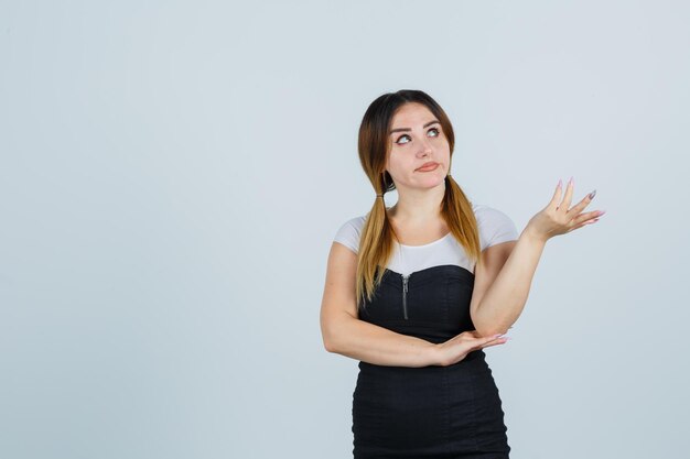 Young woman raising hand in puzzled gesture