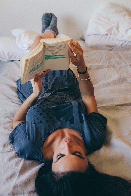 Free photo young woman reading in bed