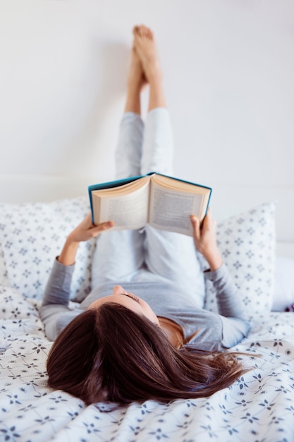 Free photo young woman reading on bed