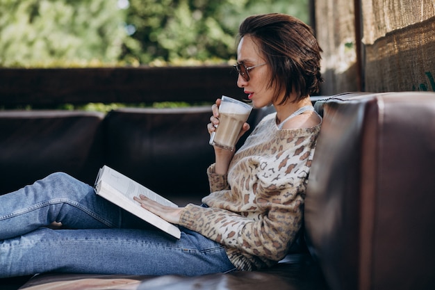 Free Photo young woman reading book and drinking coffee