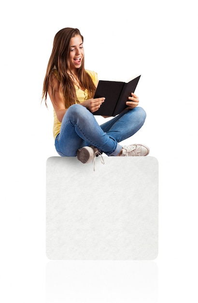 young woman reading a book sitting on a white box