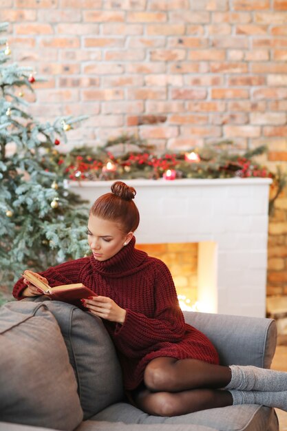 Young woman reading a book in the sofa