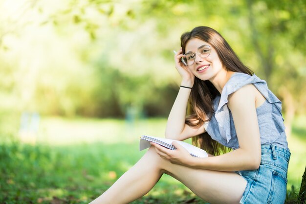 Young woman reading book under the tree during picnic in evening sunlight