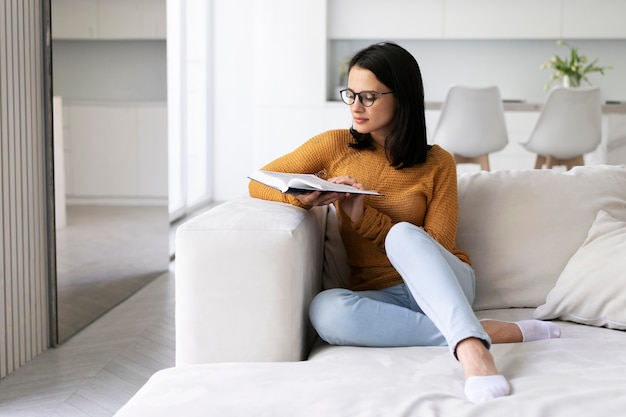 Young woman reading from a book at home