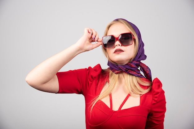 Young woman in red outfit posing on gray background. 