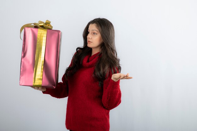 Young woman in red sweater looking at Christmas presents . 