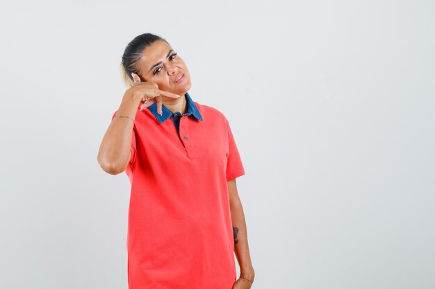 Young woman in red t-shirt stretching hand as talking on phone and looking happy , front view.