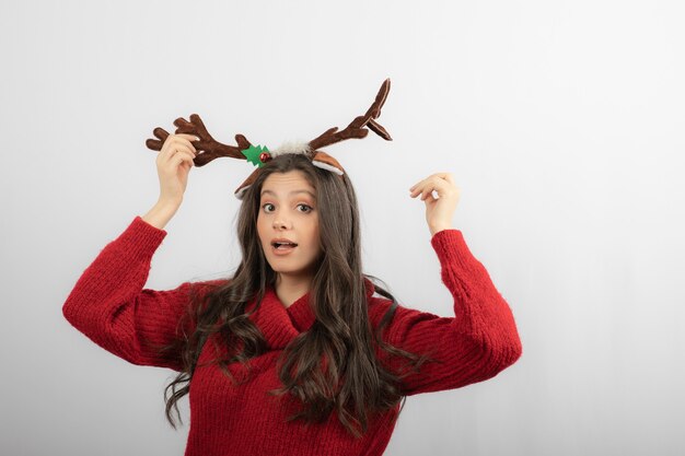 Young woman in red warm sweater and deer headband . 