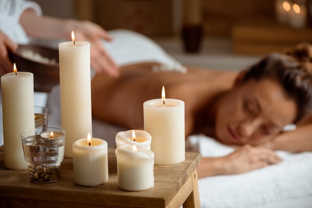 Young woman relaxing in spa salon. Focus on candles.