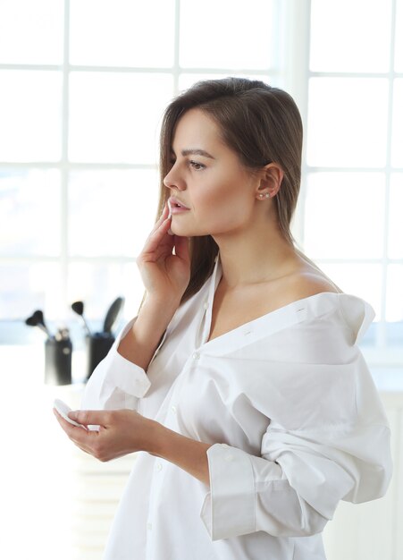 Young woman removing facial makeup with make-up remover wipes.