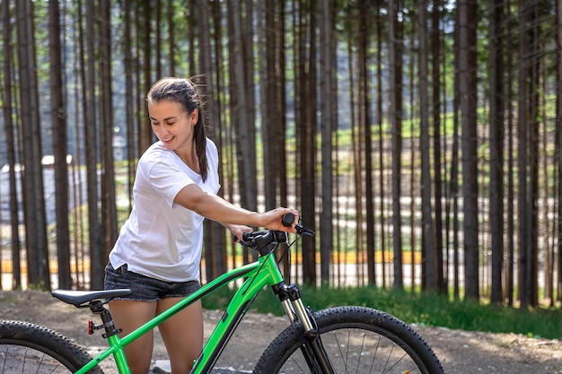 A young woman rides a bicycle in a mountainous area in the forest