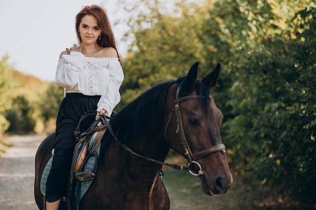 Free photo young woman riding a horse in forest