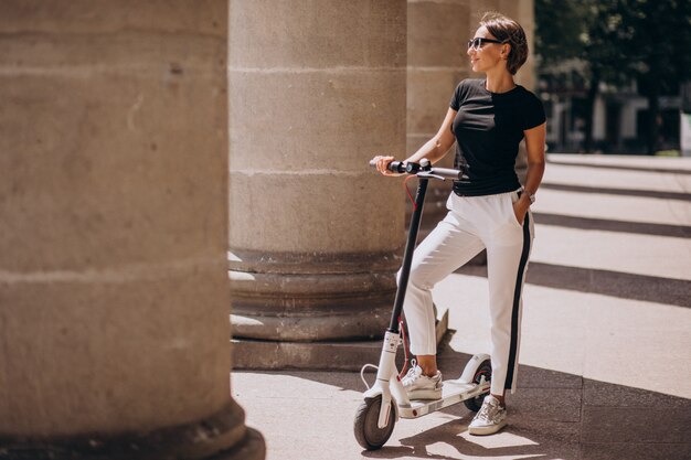 Young woman riding scotter by the university building